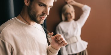pensive young man touching pendants and blonde girl on brown